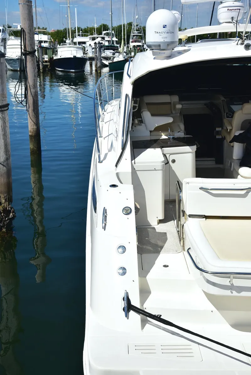 Slide: The Image of 2013 Sea Ray 410 Sundancer yacht docked at marina, showcasing sleek design and spacious deck. - 22