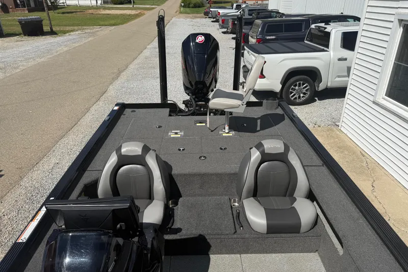 Slide: The Image of 2021 Lund 2075 Pro-V Bass boat with seating and motor, parked near trucks. - 10