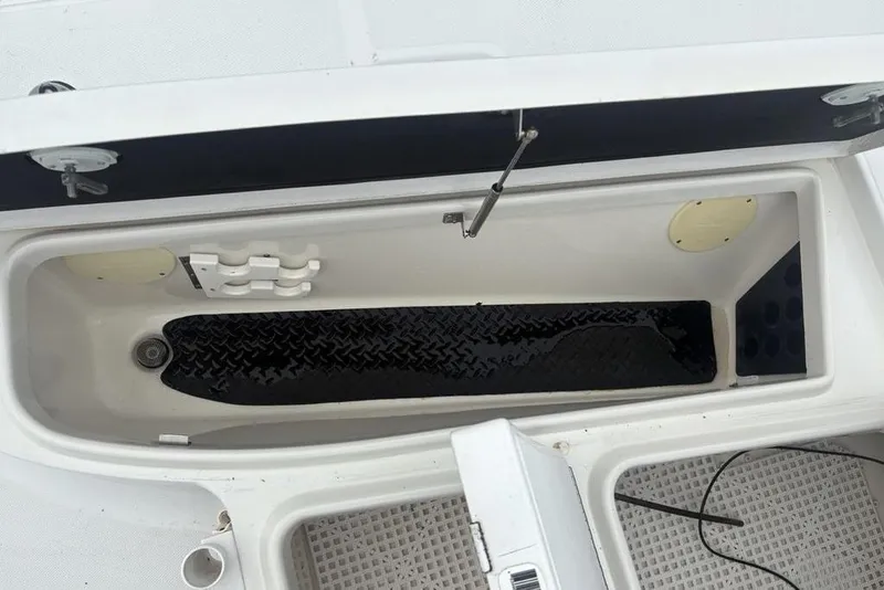 Slide: The Image of Open storage compartment on a 2003 Ranger 2300 Bay Ranger boat, featuring a black mat. - 11