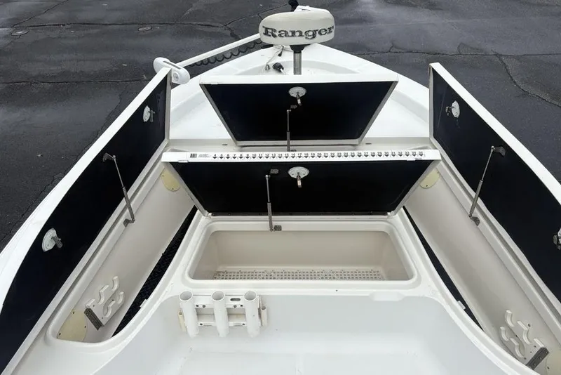 Slide: The Image of 2003 Ranger 2300 Bay Ranger boat interior with open storage compartments and rod holders. - 12