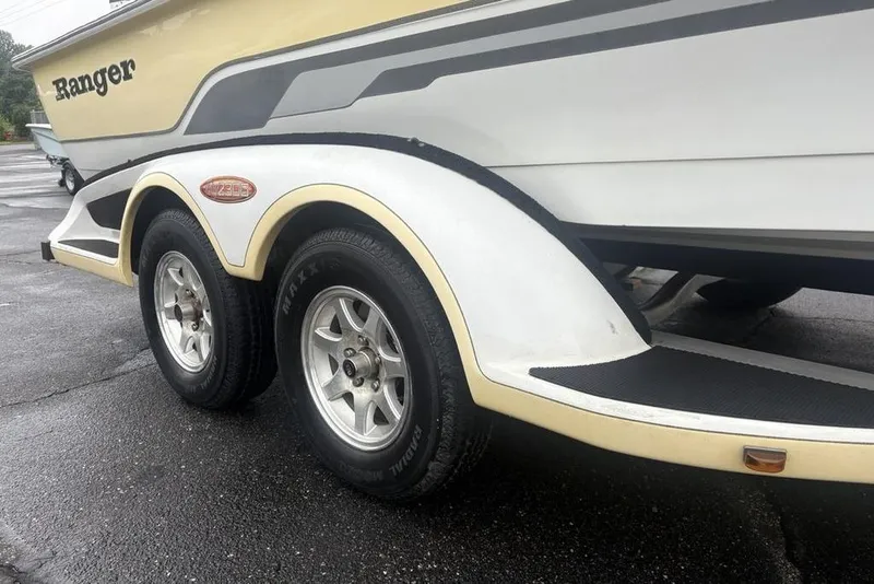 Slide: The Image of 2003 Ranger 2300 Bay Ranger boat trailer with dual wheels on wet pavement. - 5