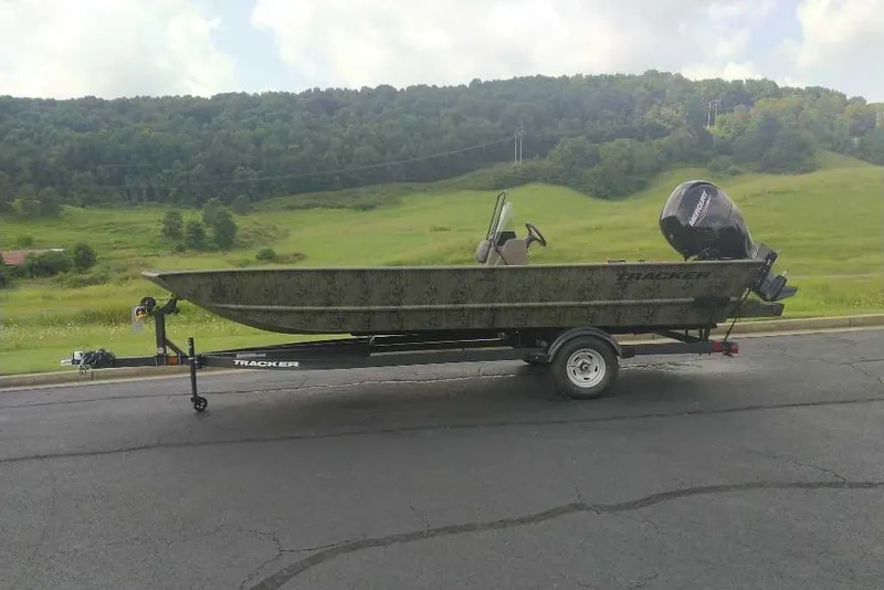 The Image of 2026 Tracker Grizzly 2072 CC boat on trailer, parked on road with scenic green hills. - 0