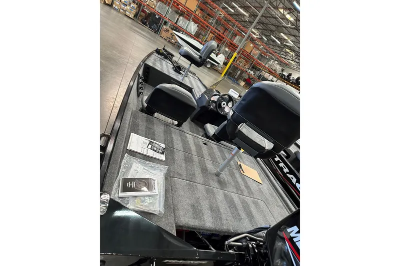 Slide: The Image of 2026 Tracker Bass Tracker Classic XL boat interior with seats and dashboard in a warehouse. - 3
