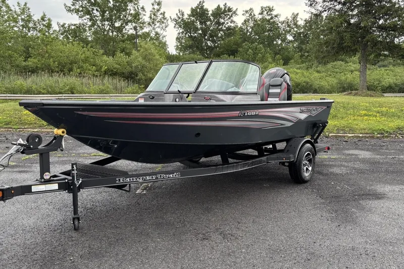 The Image of 2025 Ranger VS1682SC Angler boat on trailer, parked outdoors with lush greenery background. - 0