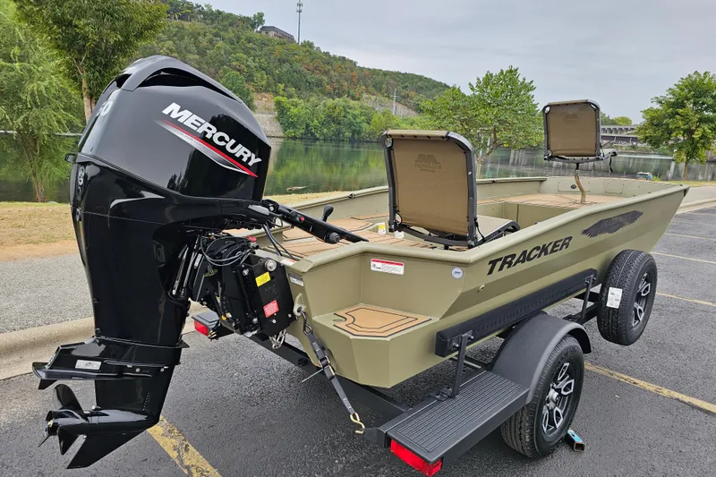 Slide: The Image of 2026 Tracker Grizzly 1650 T Prairie Wings Edition boat with Mercury engine, parked by a scenic river. - 3
