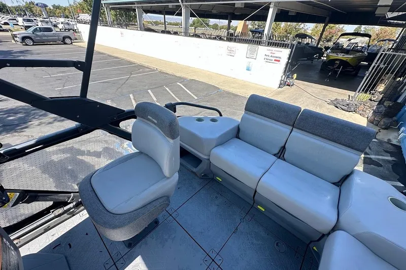Slide: The Image of 2024 Sea-Doo Switch Sport 18 interior with seating and cup holders in a parking lot. - 14