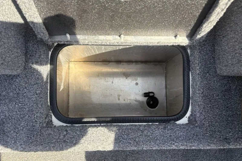 Slide: The Image of Livewell compartment in 2026 Tracker Pro Team 190 TX boat, featuring a drain plug. - 10