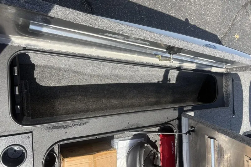 Slide: The Image of 2026 Tracker Pro Team 190 TX boat storage compartment, open and empty, on a sunny day. - 12