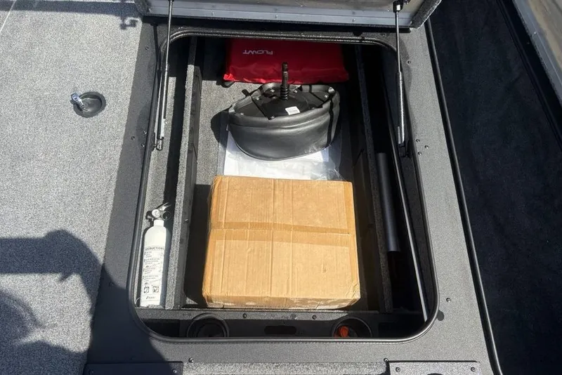 Slide: The Image of Storage compartment of 2026 Tracker Pro Team 190 TX boat with safety equipment and cardboard box. - 8