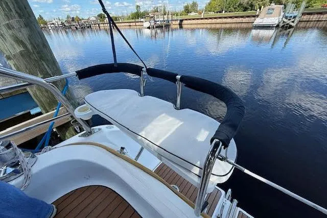 Slide: The Image of 2005 Hunter 38 sailboat deck with railing, docked by calm waters under a blue sky. - 12