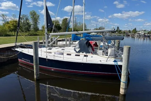 Slide: The Image of 2005 Hunter 38 sailboat docked in a serene marina under a clear blue sky. - 2