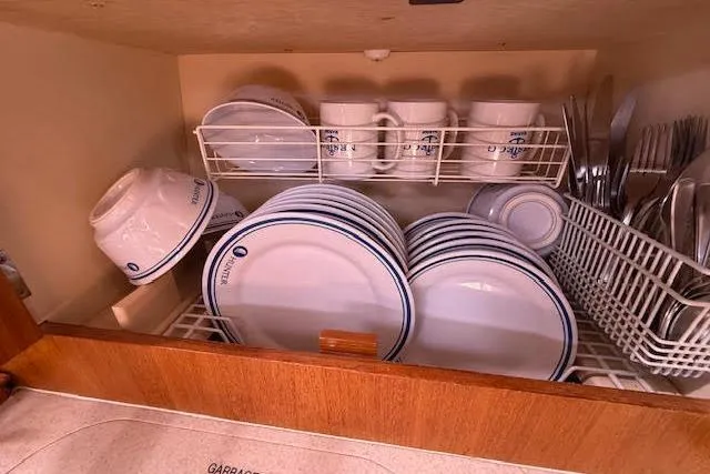 Slide: The Image of Cabinet with neatly arranged plates, bowls, mugs, and cutlery on a Hunter 38, 2005 model. - 31