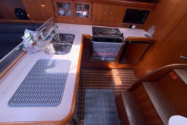 Slide: The Image of 2005 Hunter 38 yacht interior kitchen with sink, stove, and wooden cabinetry. - 36