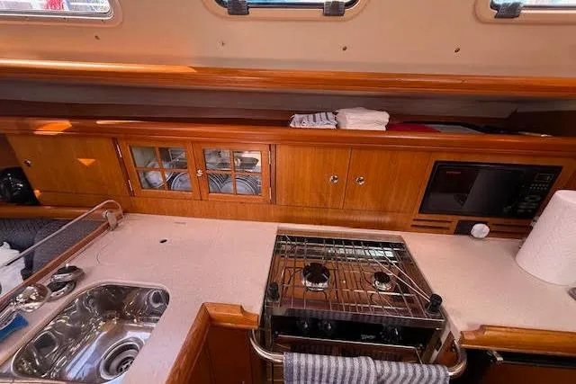 Slide: The Image of Interior view of a 2005 Hunter 38 yacht kitchen with stove, sink, and wooden cabinetry. - 37