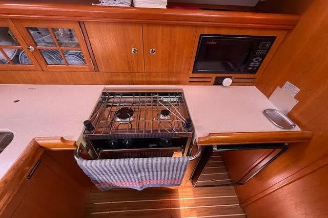 Slide: The Image of 2005 Hunter 38 yacht kitchen with stove, microwave, and wooden cabinetry. - 40