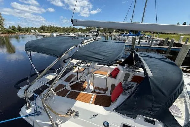 Slide: The Image of 2005 Hunter 38 sailboat with blue canopy docked at marina under clear sky. - 6