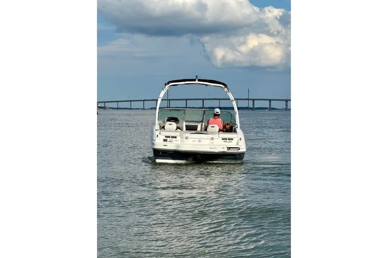 Slide: The Image of 2017 Chaparral 21 H2O Sport boat cruising on a calm waterway with a bridge in the background. - 3
