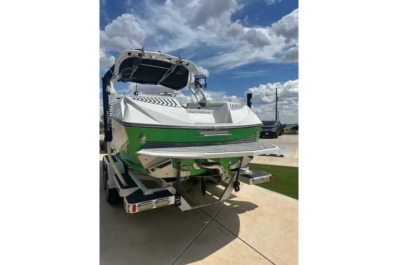 Slide: The Image of 2017 Nautique Super Air Nautique G21 boat, green and white, parked outdoors under a cloudy sky. - 20