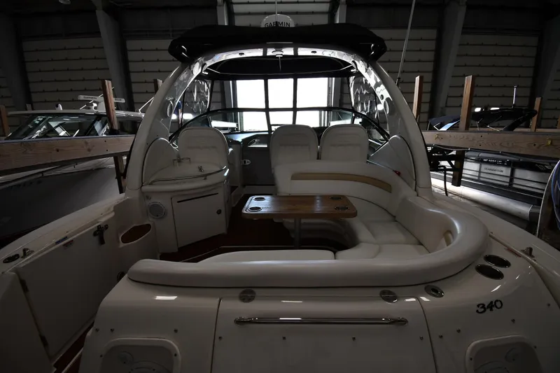 Slide: The Image of 2008 Sea Ray 340 Sundancer interior with white seating and wooden table in a boatyard. - 10