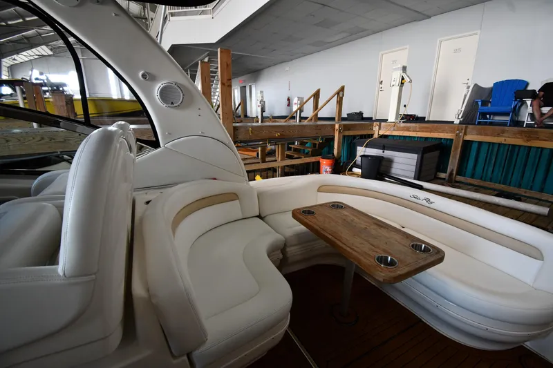 Slide: The Image of 2008 Sea Ray 340 Sundancer interior with white seating and wooden table in a marina setting. - 22