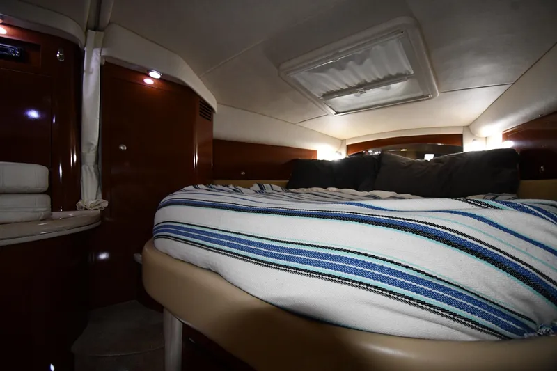 Slide: The Image of 2008 Sea Ray 340 Sundancer cabin interior with cozy bed and striped bedding. - 33