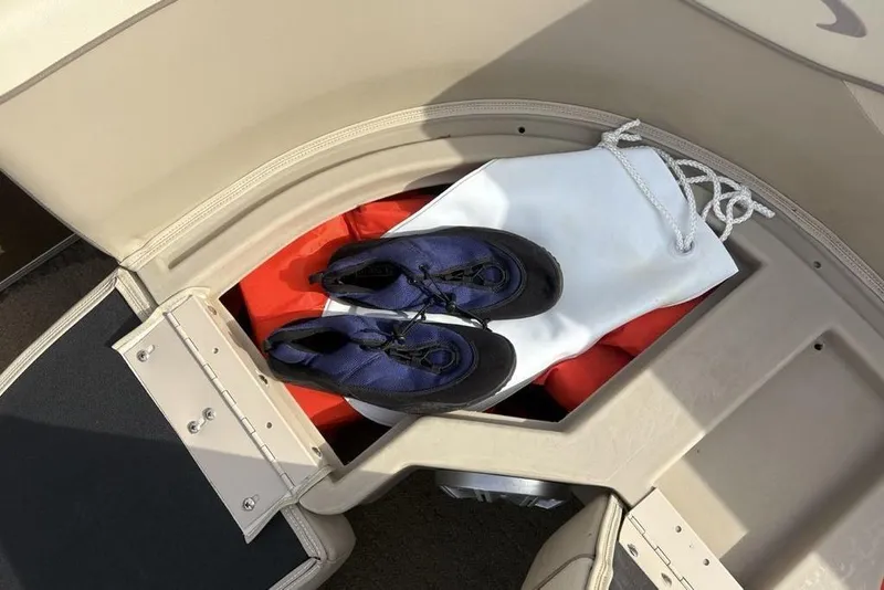 Slide: The Image of Storage compartment on 2015 Bennington 24 SSRX boat with shoes and a white bag. - 10