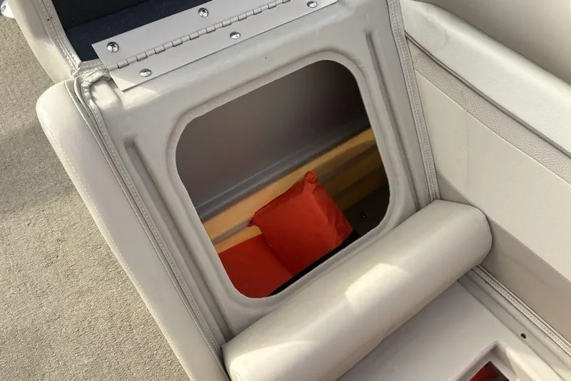 Slide: The Image of Open storage compartment in a 2015 Bennington 24 SSRX boat, revealing a red life jacket. - 11