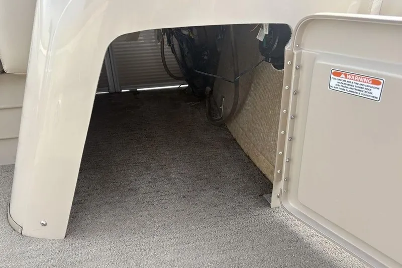 Slide: The Image of 2015 Bennington 24 SSRX storage compartment with open door and warning label. - 16