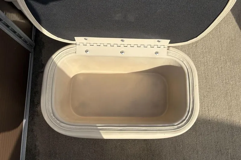 Slide: The Image of Open storage compartment on a 2015 Bennington 24 SSRX boat, beige interior. - 18
