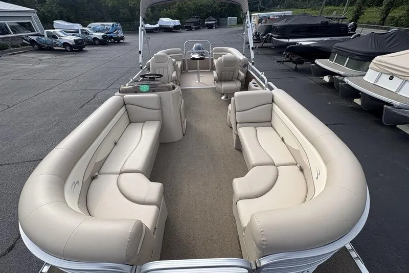 Slide: The Image of 2015 Bennington 24 SSRX pontoon boat with spacious seating and canopy in a parking lot. - 27