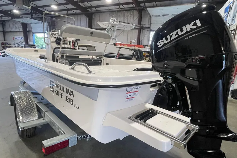 Slide: The Image of 2026 Carolina Skiff E18 JVX CC boat with Suzuki engine in a showroom. - 4