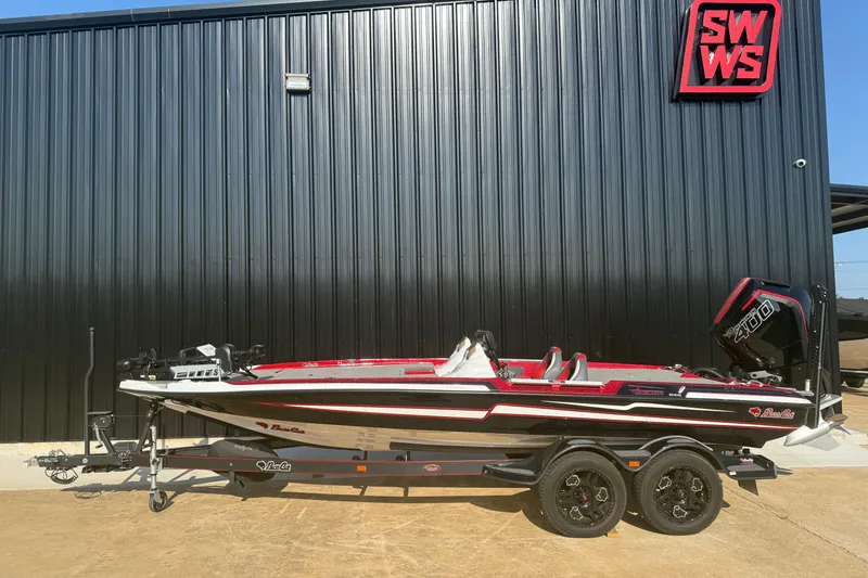 Slide: The Image of 2023 Bass Cat Jaguar STS boat on trailer, parked outside a black building. - 0