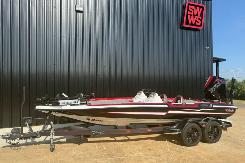 Slide: The Image of 2023 Bass Cat Jaguar STS boat on trailer, parked outside black building with SWWS sign. - 1