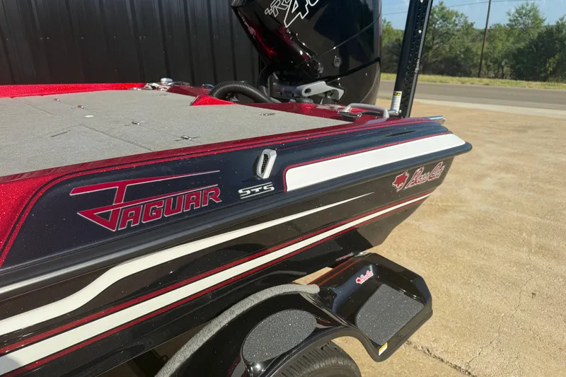 Slide: The Image of 2023 Bass Cat Jaguar STS boat, red and black design, parked outdoors. - 11