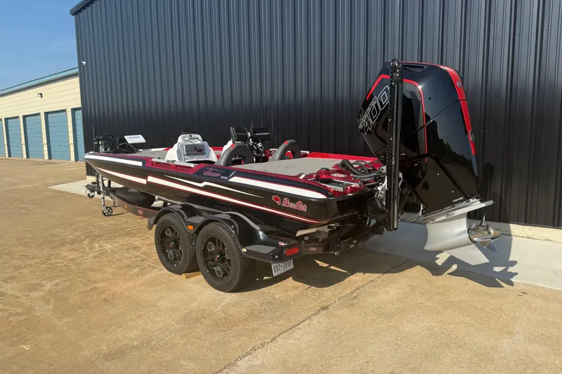 Slide: The Image of 2023 Bass Cat Jaguar STS boat with powerful outboard motor, parked near storage units. - 12