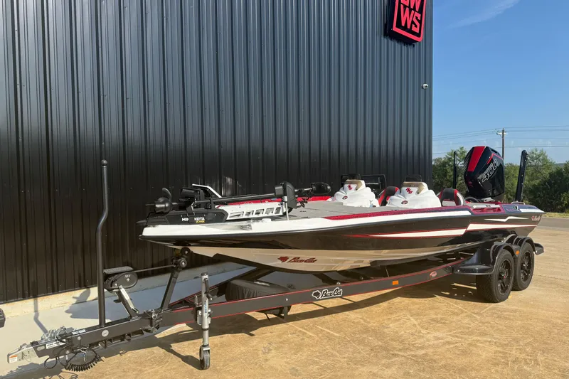 Slide: The Image of 2023 Bass Cat Jaguar STS boat on trailer, parked beside a black building. - 4