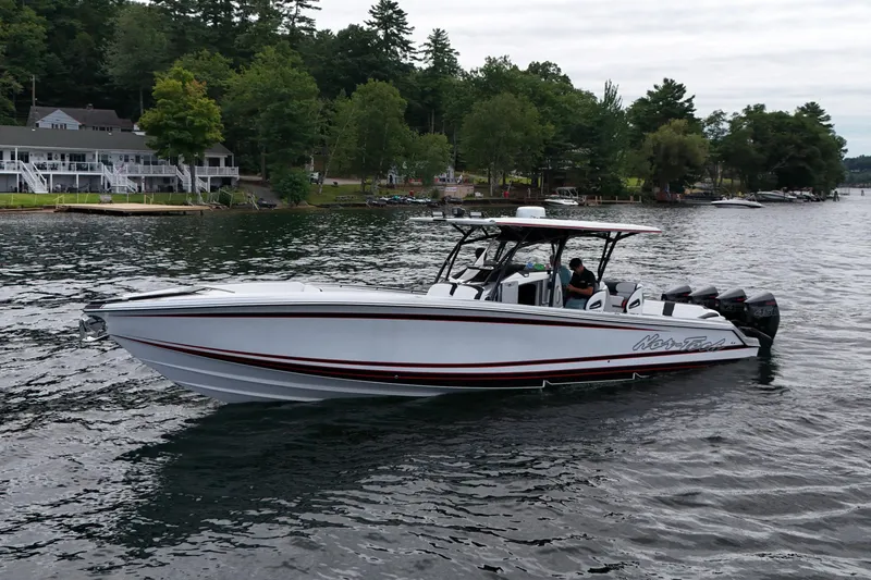Slide: The Image of 2022 Nor-Tech 390 Sport Center Console boat on a scenic lake with lush greenery. - 3