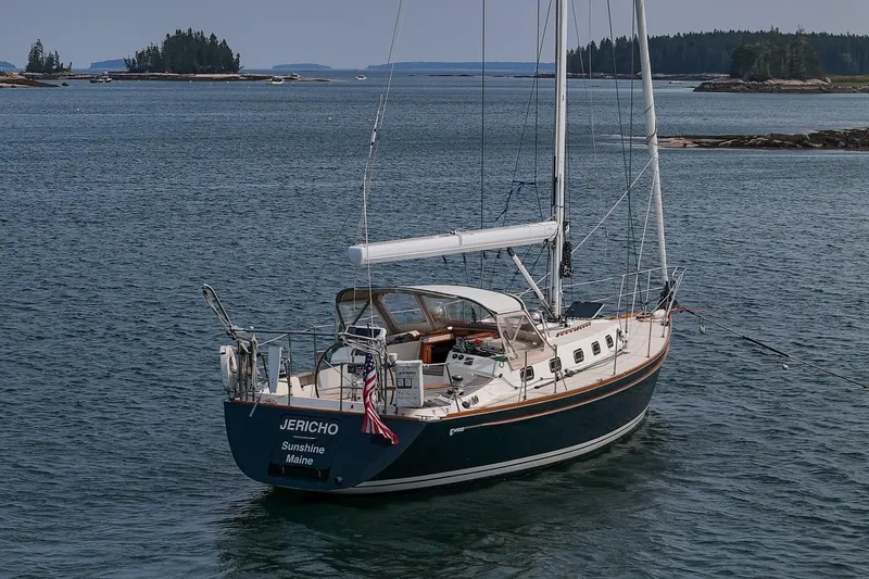 Slide: The Image of Sailboat Tartan 4100 (2002) named Jericho on calm waters near forested islands. - 2