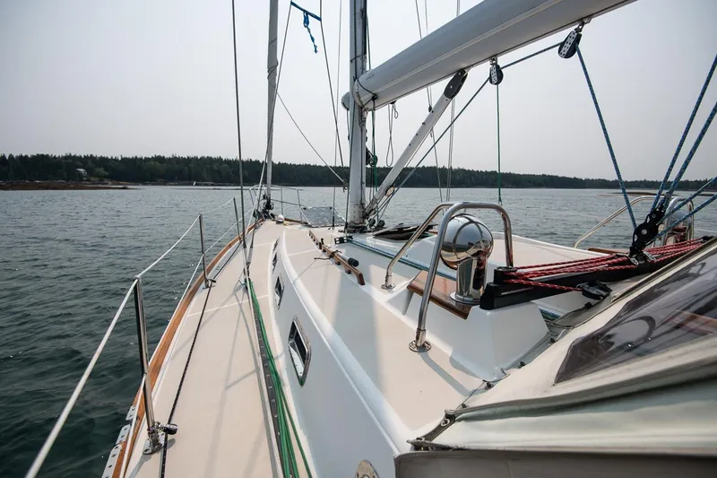 Slide: The Image of Sailing yacht Tartan 4100, 2002 model, cruising on calm waters near a forested shoreline. - 22