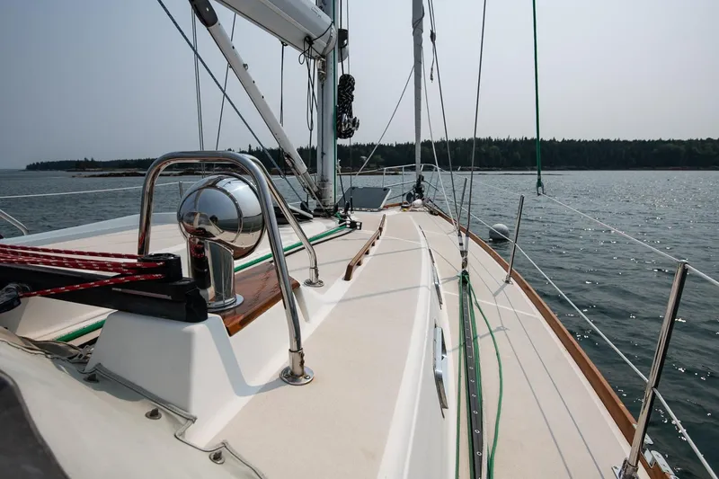 Slide: The Image of Sailing on a 2002 Tartan 4100 yacht, calm waters, clear sky, forested shoreline. - 24