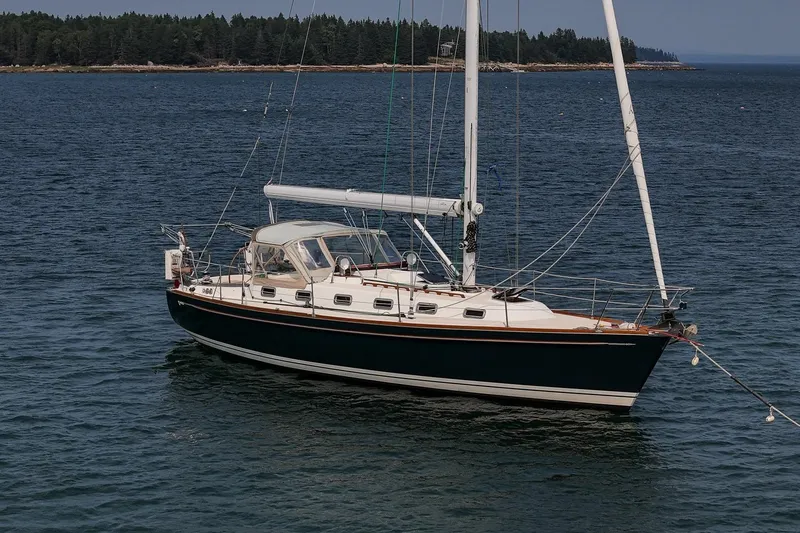 Slide: The Image of 2002 Tartan 4100 sailboat on calm water with forested shoreline in background. - 9