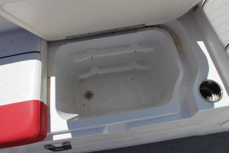 Slide: The Image of 2022 Tahoe 2150 boat storage compartment with red and white seating and cup holder. - 15