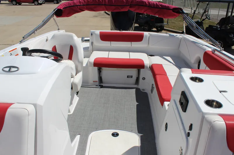 Slide: The Image of 2022 Tahoe 2150 boat interior with red and white seating, steering wheel, and cup holders. - 23