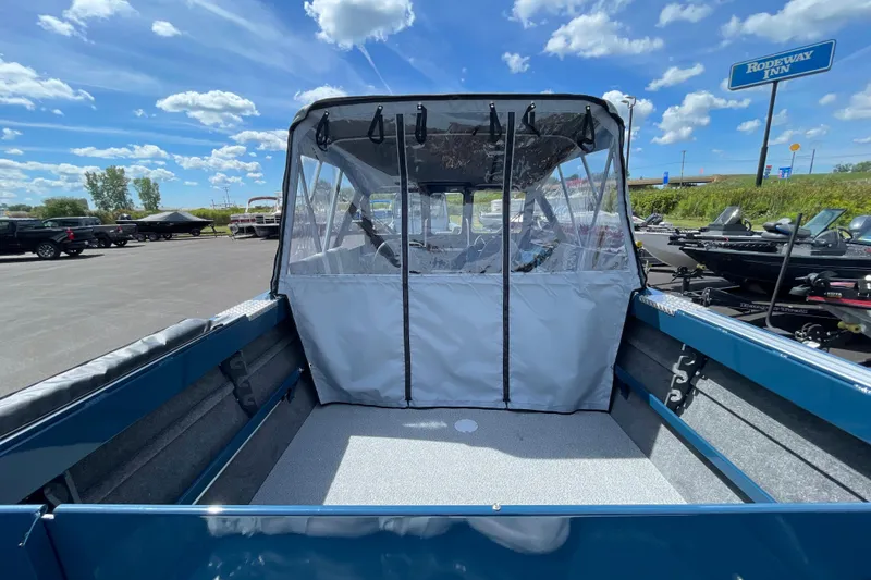 Slide: The Image of 2026 Hewescraft 200 ProV boat with canopy, parked outdoors under a blue sky. - 5
