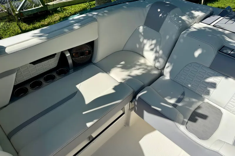 Slide: The Image of 2023 MasterCraft X24 boat interior with white and gray seating, cup holders, and speaker. - 11