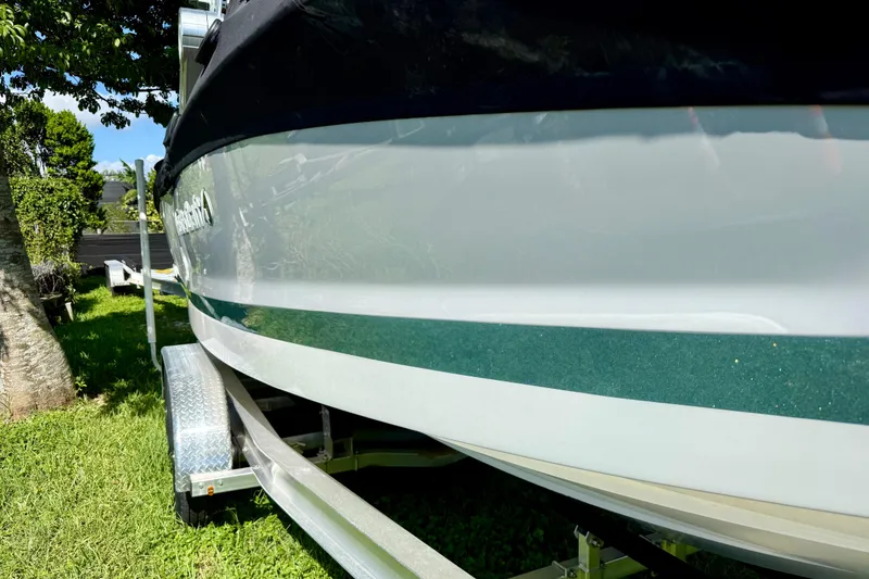Slide: The Image of 2023 MasterCraft X24 boat on trailer, parked on grass under a tree. - 8