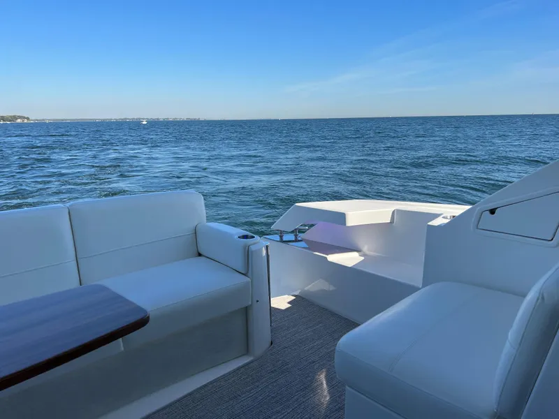 Slide: The Image of 2021 Tiara Yachts C49 Coupe deck with ocean view, featuring white seating and a wooden table. - 10