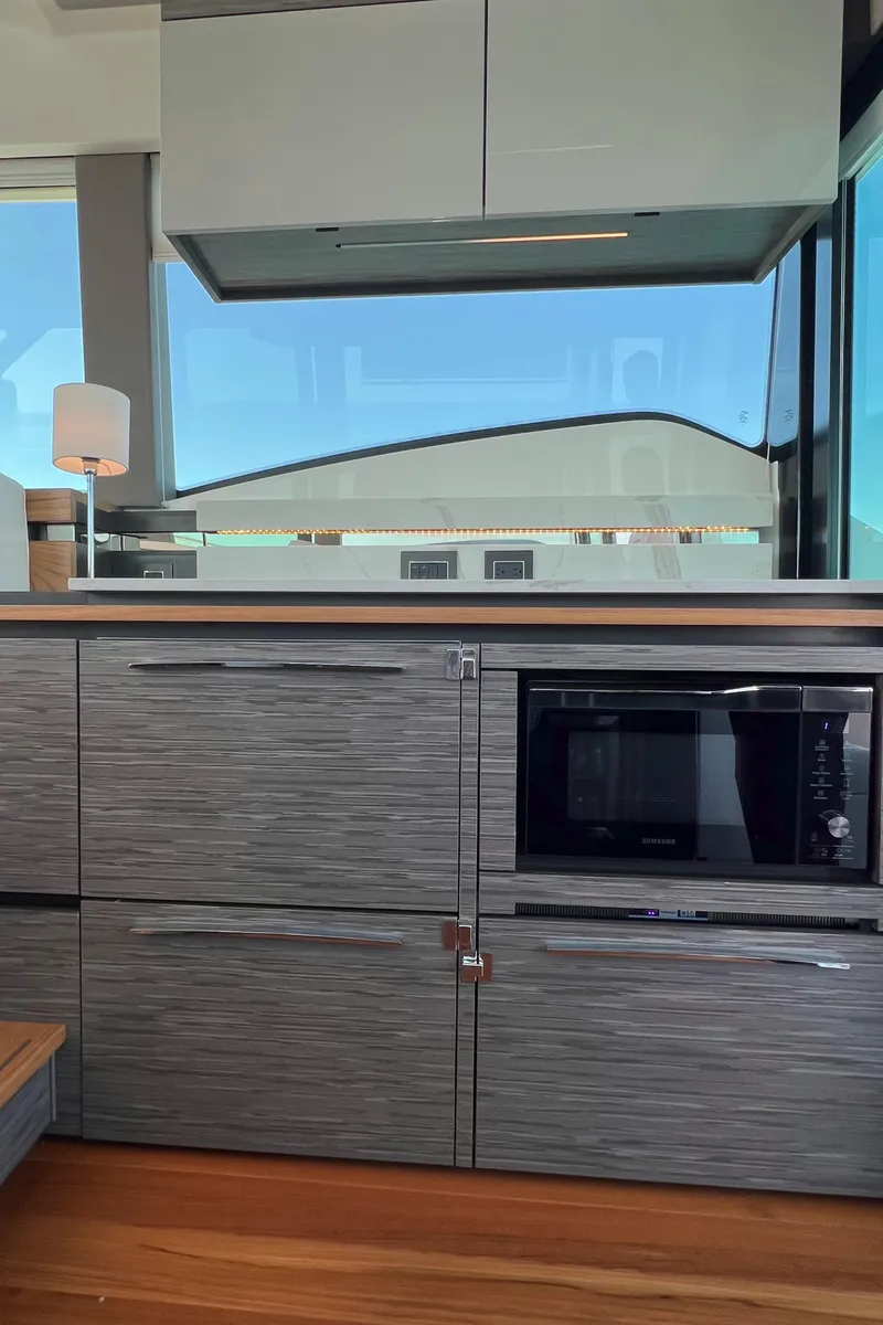 Slide: The Image of 2021 Tiara Yachts C49 Coupe interior kitchen with modern cabinetry and microwave. - 15