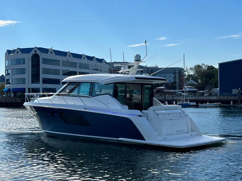 Slide: The Image of 2021 Tiara Yachts C49 Coupe cruising in a marina with modern buildings in the background. - 3