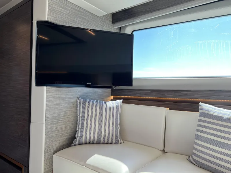 Slide: The Image of Interior of 2021 Tiara Yachts C49 Coupe with TV, sofa, and striped pillows. - 39
